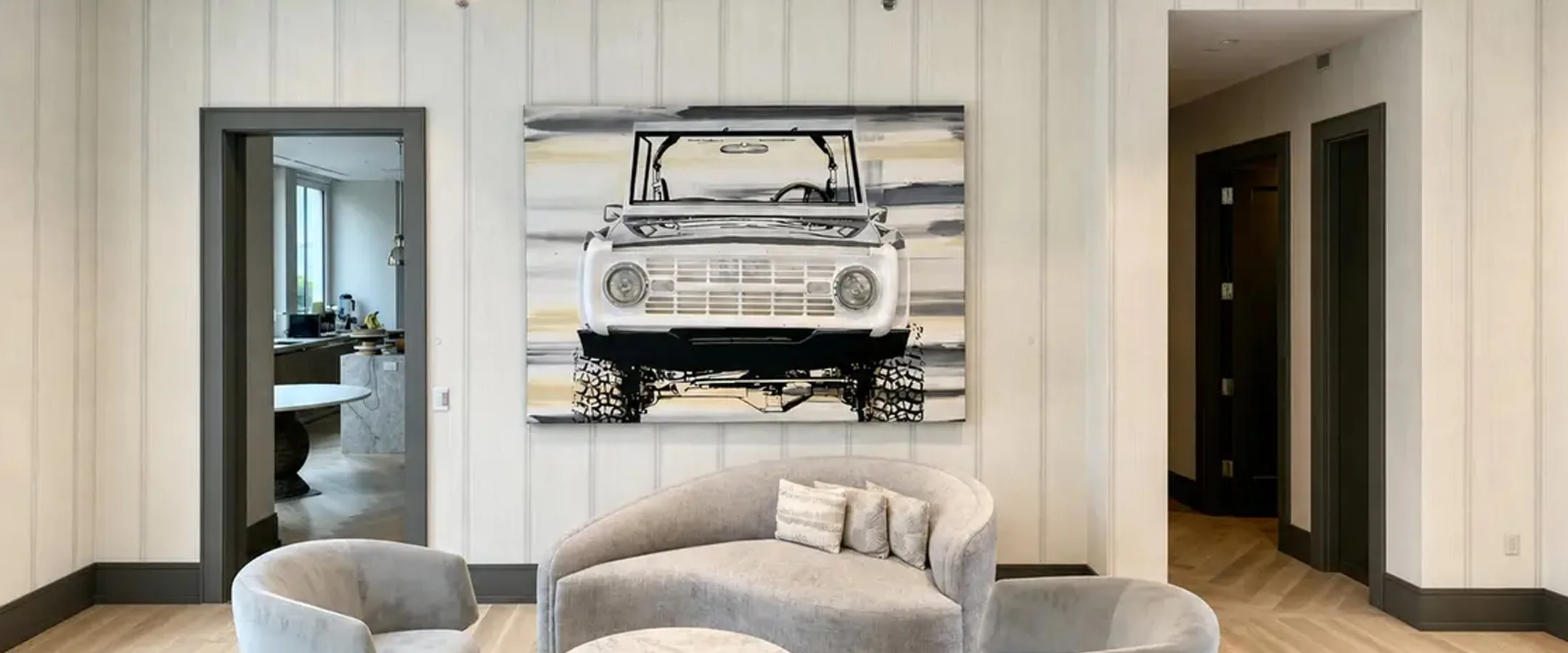 The ’69 Bronco painting by Erik Skoldberg — a Pop Collection canvas with the chrome grille mounted into it — hung above a curved sofa in a panelled room